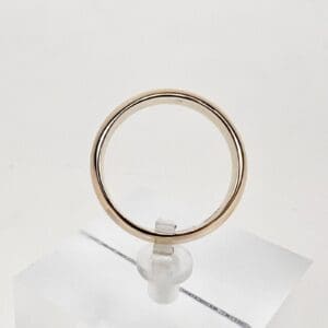 Gold ring displayed on a clear stand.
