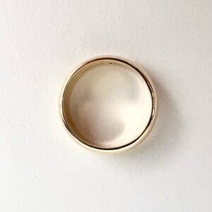 Gold wedding ring on white surface.
