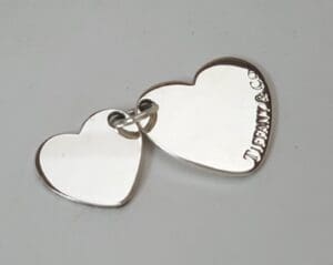 Two silver heart-shaped pendants linked together.