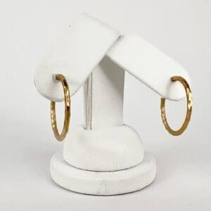 Gold hoop earrings on white display stand.