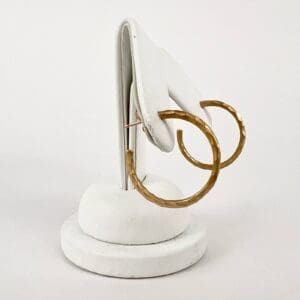 Gold hoop earrings on white stand.