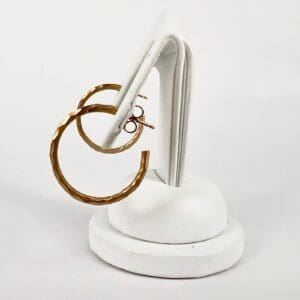 Gold hoop earrings on white stand.