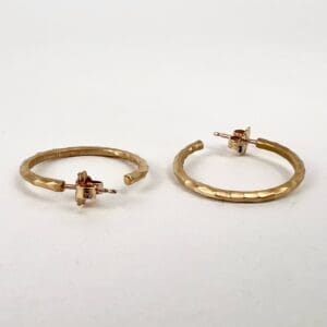 Gold textured hoop earrings on white background.