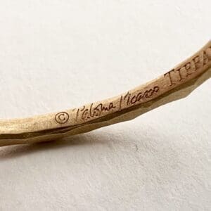 Gold bracelet engraved with designer's signature.