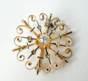 Ornate gold brooch with central diamond.