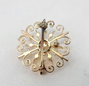 Gold ornate brooch with intricate design.