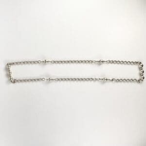 Silver chain with round beads on white.
