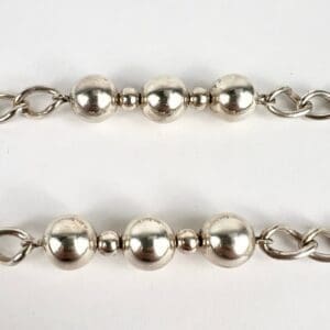 Silver beaded chains on white background.
