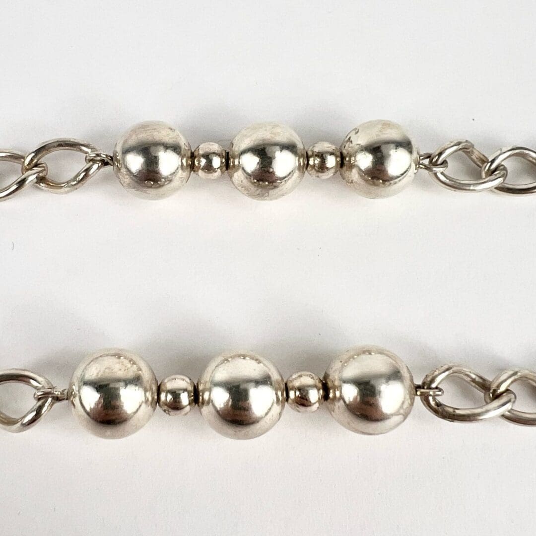 Silver beaded chains on white background.