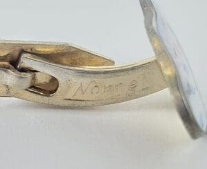Silver cufflink with engraved text detail.