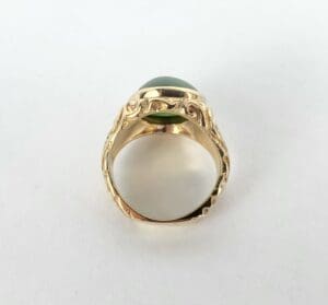 Gold ring with green gemstone and engravings.