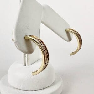 Gold hoop earrings on white display stand.