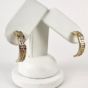 Gold hoop earrings on white stand.
