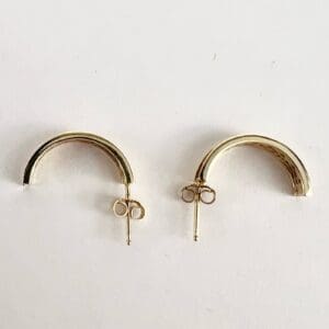 Gold half-hoop earrings on white background.