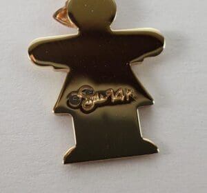 Gold figure pin with engraved signature.