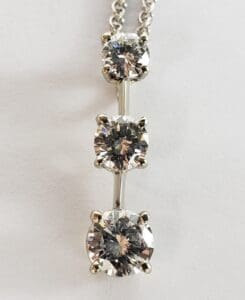 Three diamond stones on a silver necklace.