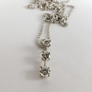 Silver necklace with three diamond pendants.