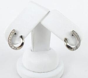 Silver diamond hoop earrings on display stand.