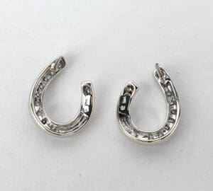 Silver horseshoe-shaped earrings on white background.