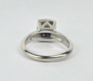 Silver ring with geometric design on top.