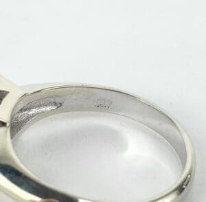 Silver ring with engraved hallmark inside band.