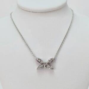 Silver butterfly necklace on display stand.