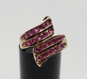 Gold ring with pink gemstones on display.