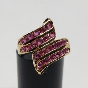 Gold ring with pink gemstones on display.