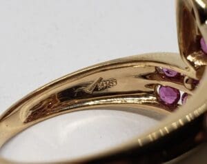 Gold ring with pink gemstone details.
