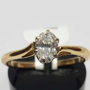 Gold ring with oval diamond solitaire.