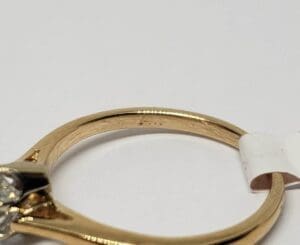 Gold ring with diamond and white tag.