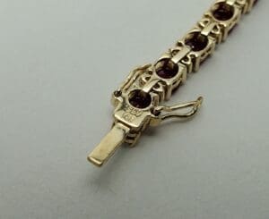 Gold bracelet with red gemstones clasp.