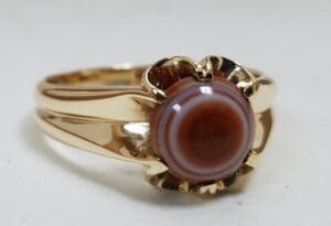 Gold ring with a round, striped gemstone.