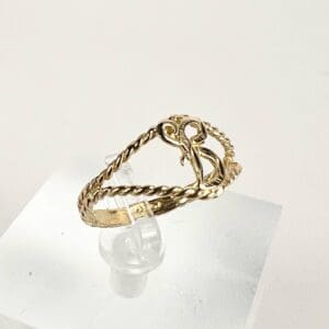 Gold twisted ring on clear display stand.
