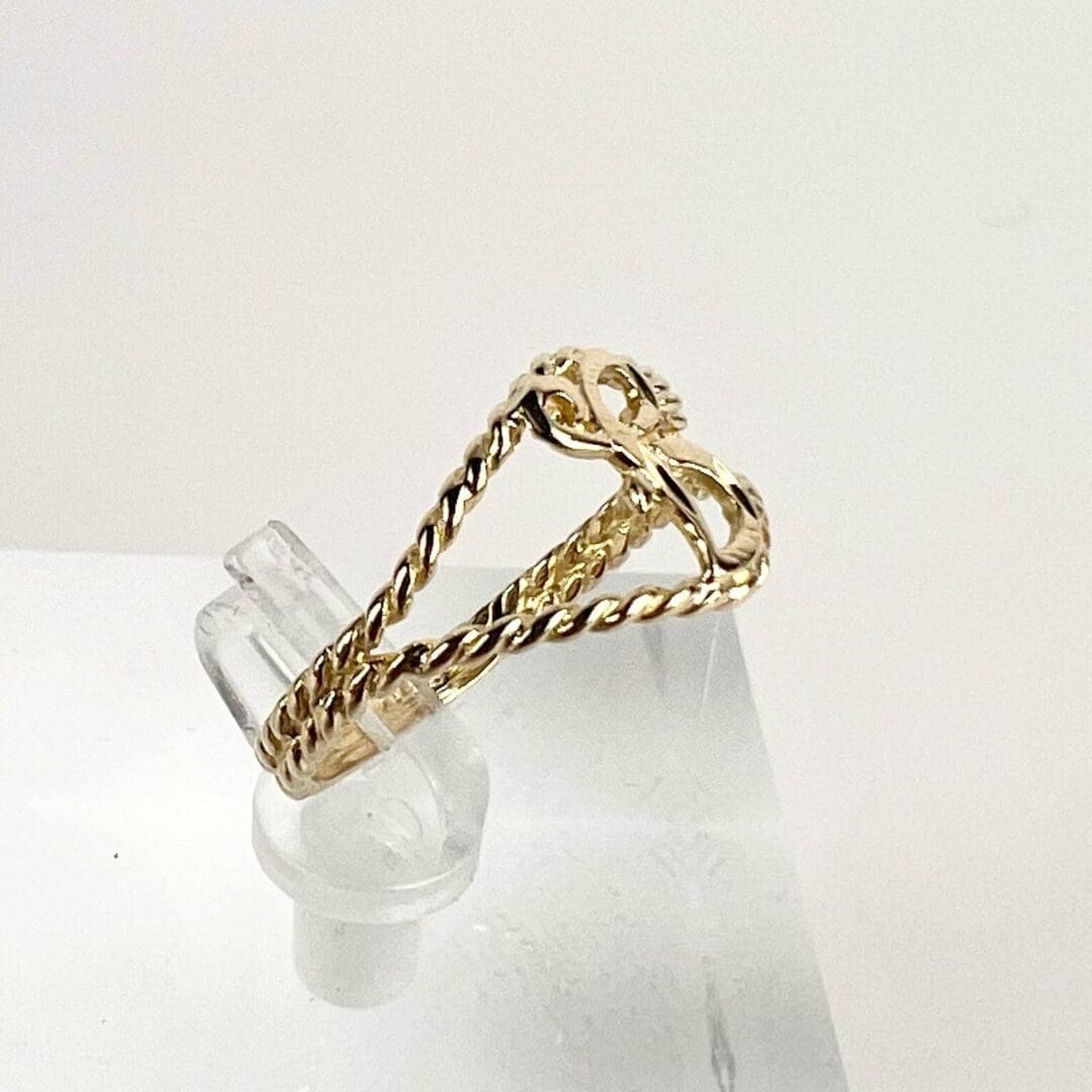Gold twisted ring on clear display stand.