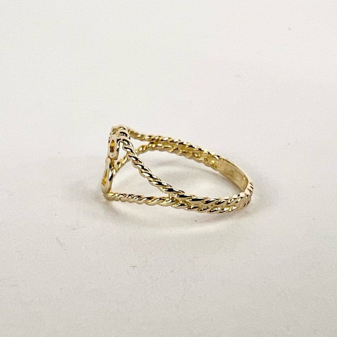 Gold twisted band ring on white background.