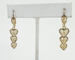 Gold heart-shaped dangling earrings on display.