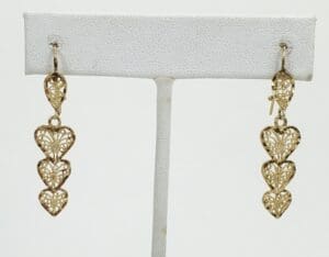 Gold heart-shaped dangle earrings on display.