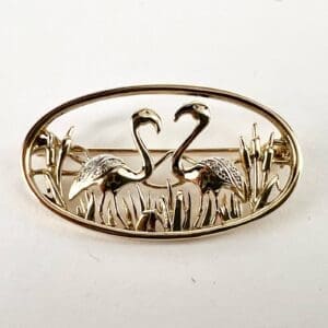 Gold flamingo brooch with decorative details.