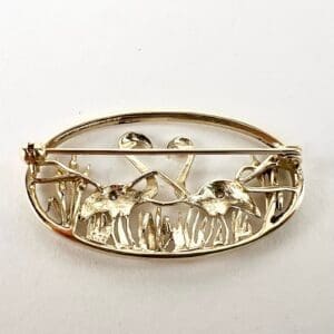 Gold brooch with crane and reeds design.