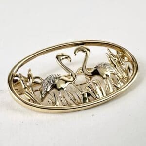 Gold flamingo brooch with intricate detailing.
