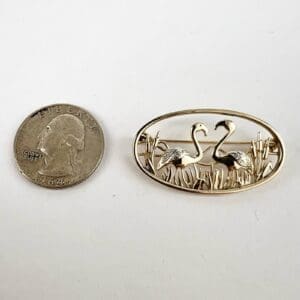 Quarter and flamingo-themed brooch on display.