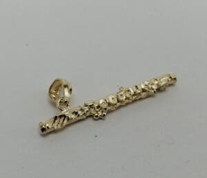 Gold flute pendant with decorative details.