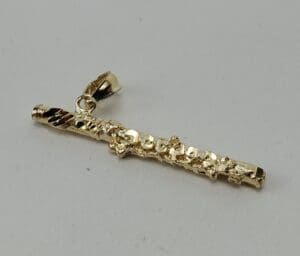 Gold flute pendant on a white background.