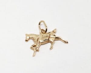 Gold horse pendant on white background.