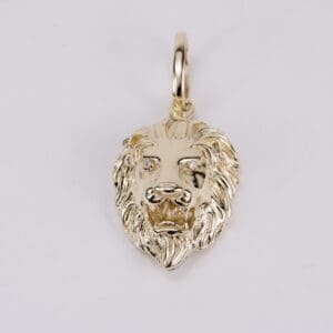 Gold lion head pendant on white background.