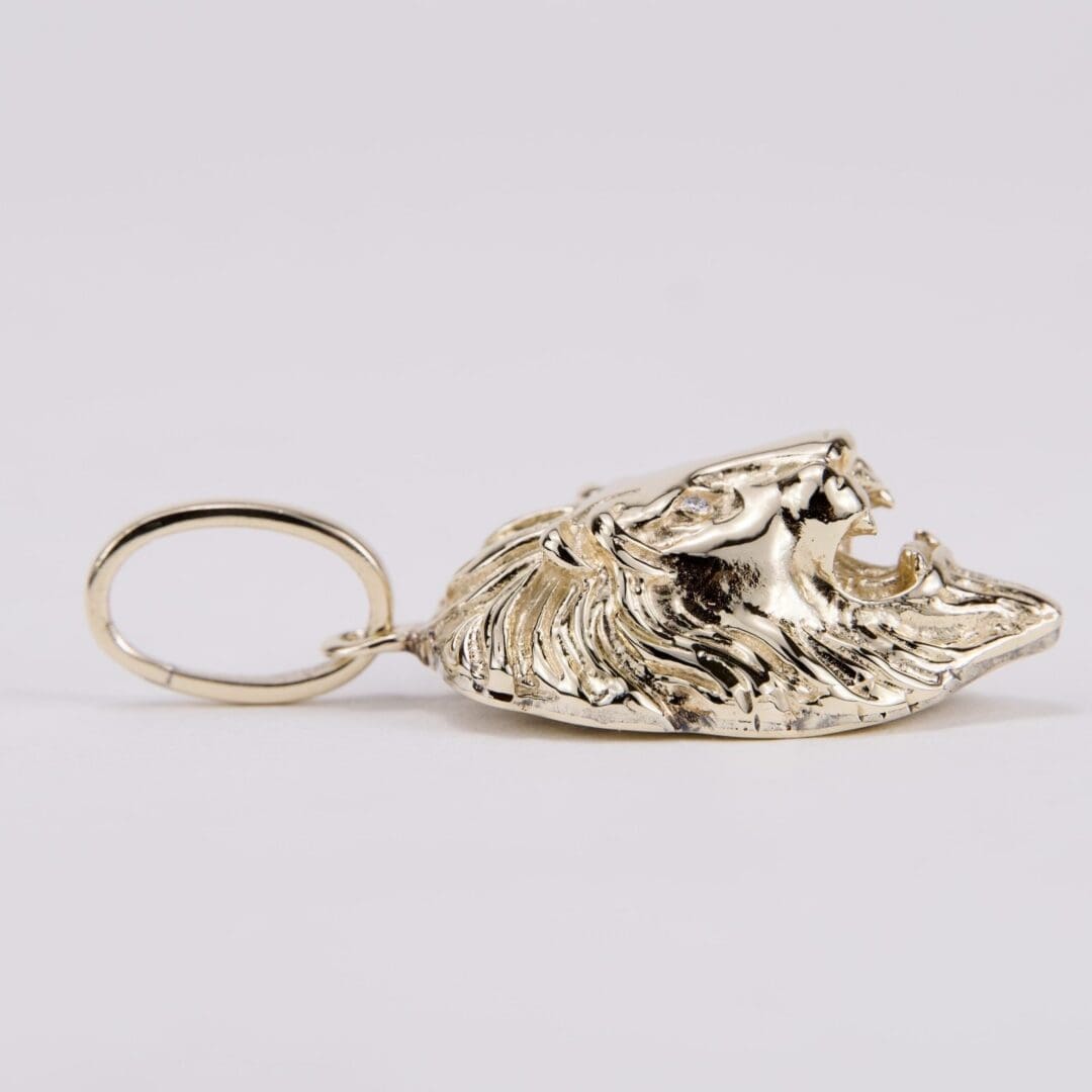 Gold lion head keychain on display.