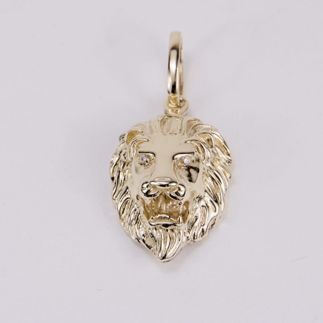 Gold lion head pendant on white background.