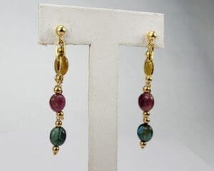 Gold earrings with red and green beads.