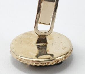 Gold cufflink with round base and clasp.